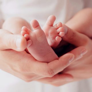 Parent holding in hands feet of newborn baby. Baby legs. Legs newborn in parents hand. Selective focus